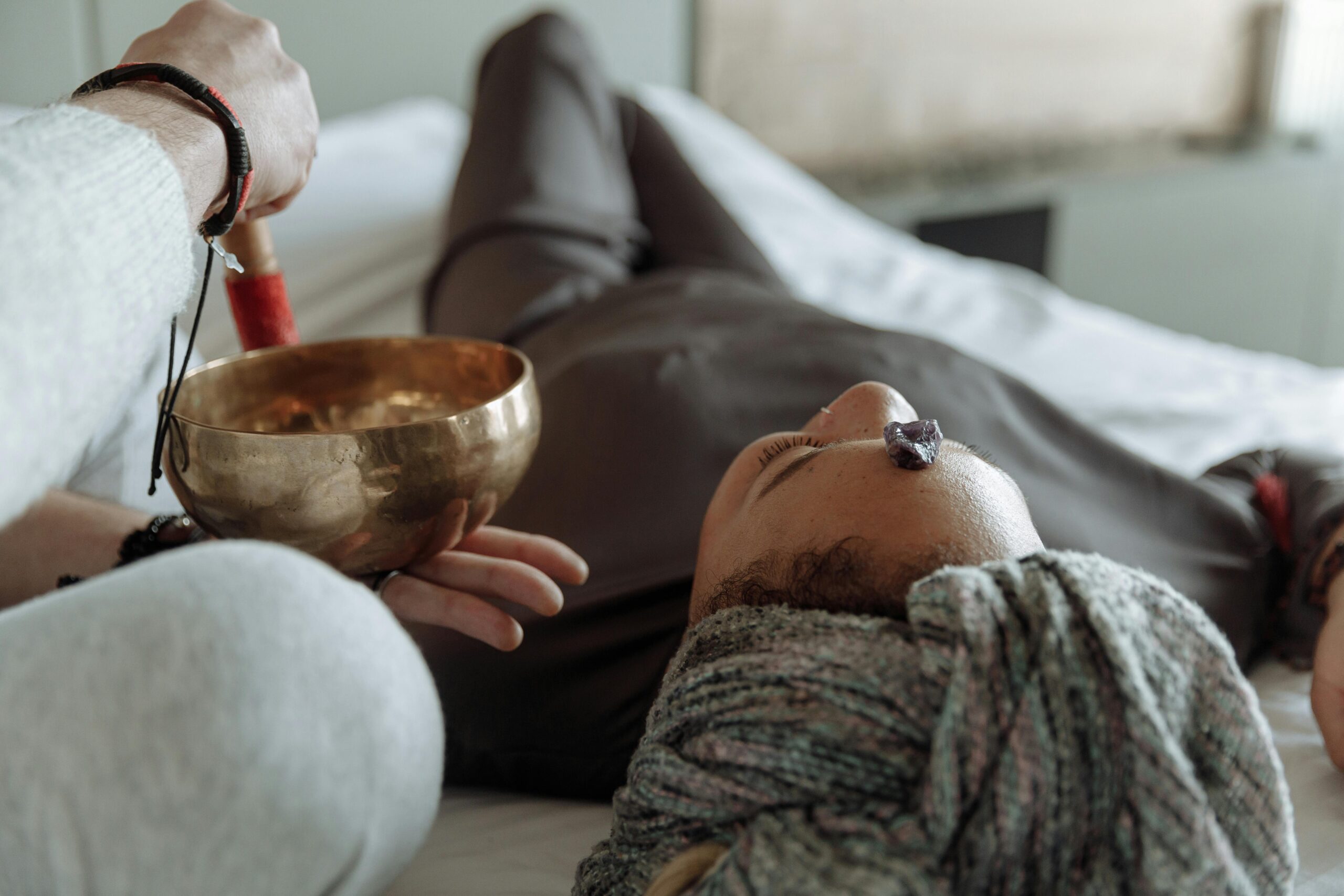 Home A serene relaxation therapy session with a Tibetan singing bowl and crystal on forehead, promoting spiritual healing.